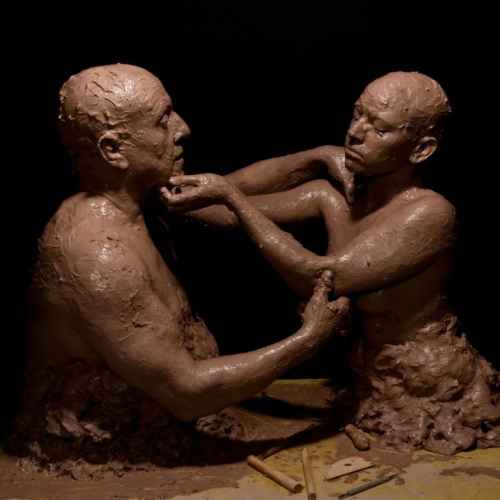 photograph of two people covered in clay